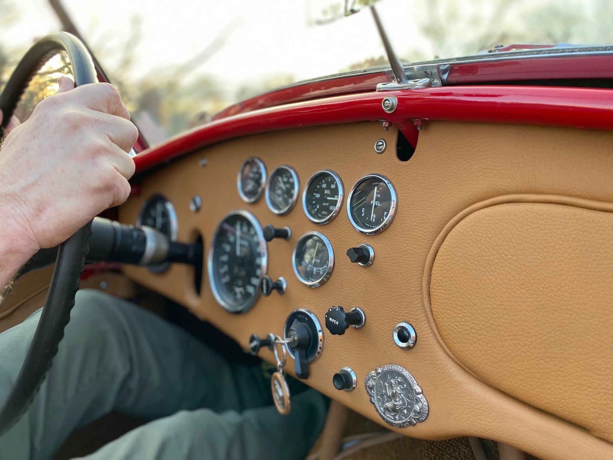 Hand on the wheel of a restored classic, dashboard gauges